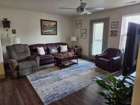 Montrose apartment for rent - A living room with a brown leather couch, a grey armchair, a brown armchair, a coffee table, and a ceiling fan.